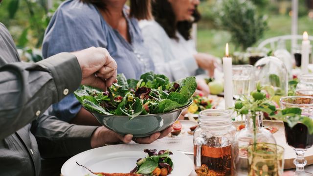 Passing salad at table outside