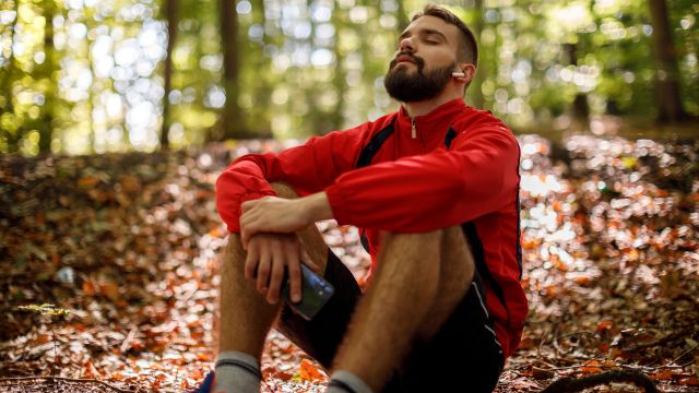 A young man takes a deep breath outside in nature. 