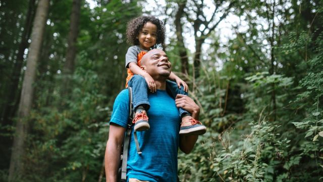 man hikes with son in the woods