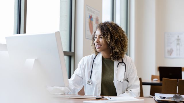 Doctor looking up patient records on a desktop computer.