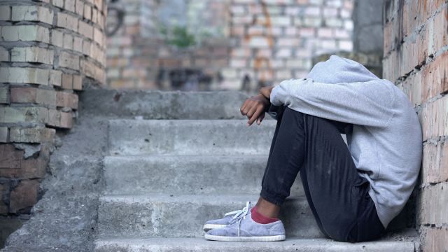 teen sitting on stairway with head in knees