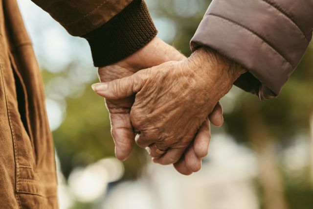 elderly couple holding hands