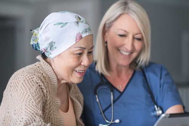 a white female healthcare provider shows test results to an elderly Asian cancer patient