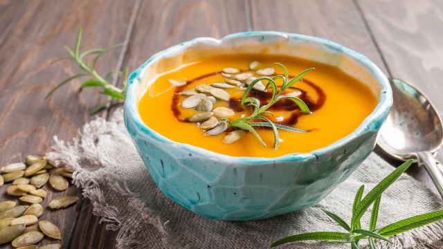 Roasted pumpkin soup with balsamic and pumpkin seeds on wooden background, close up