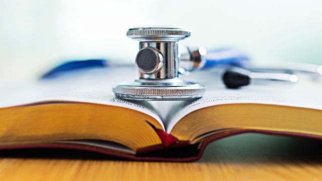 A stethoscope rests atop a medical dictionary. 