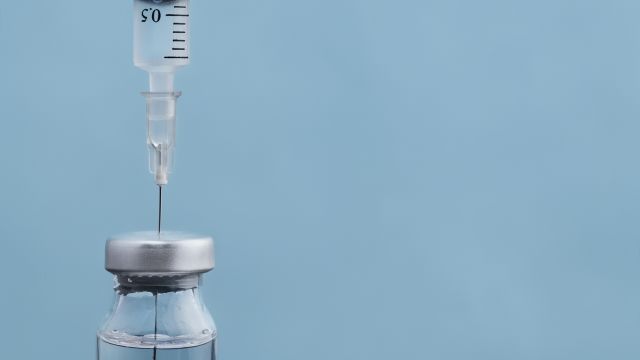 A vial and syringe on a blue background. Biologic therapies for psoriasis are given as injections or infusions.