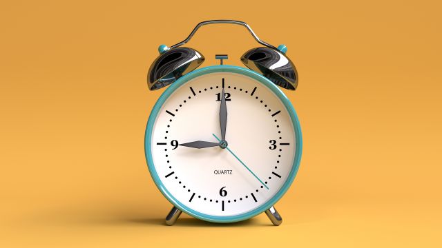 A manual clock sits on an orange background.