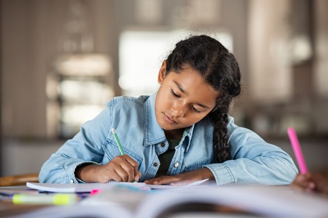 Young boy looks frustrated as he sits at table doing schoolwork.