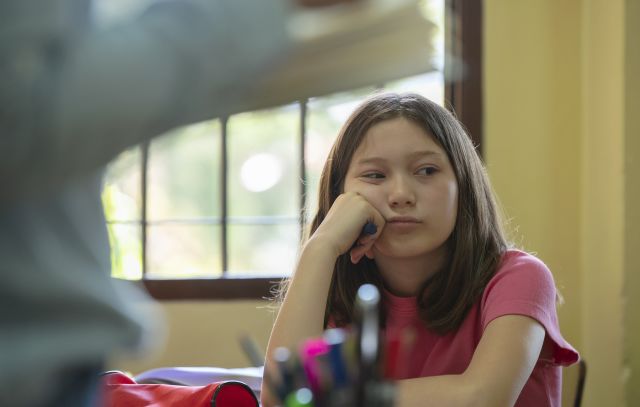 young girl with head resting on hand not paying attention in class