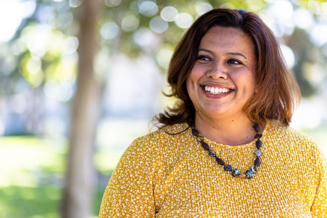 a happy Latina person smiles and looks off camera