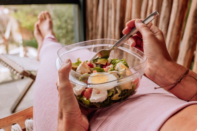View of yummy vegetarian salad, woman sitting and relaxing on a chair,