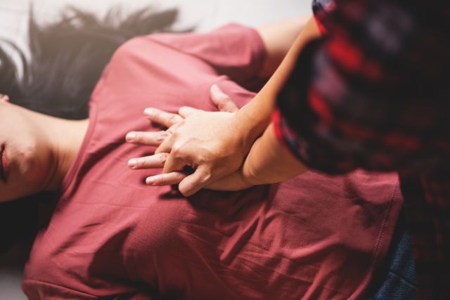 Close up of a woman administrating CPR on woman lying unconscious in home