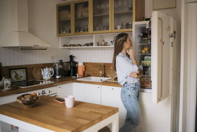 Young woman searching food inside a refrigerator at home