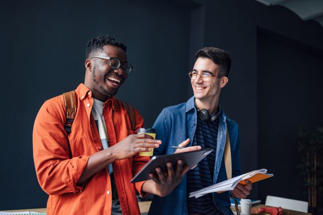 Two young professional men walking together laughing at work