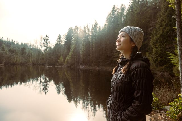 Young woman out for a hike during the early morning hours near a lake in a forest area