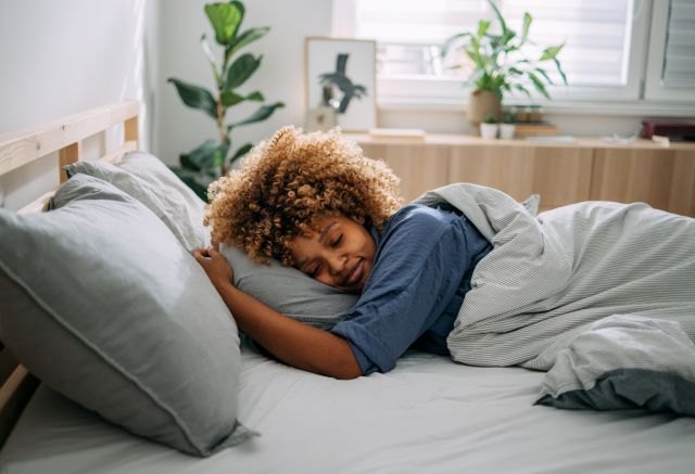 Woman sleeping peacefully on her stomach in bed in the morning hours