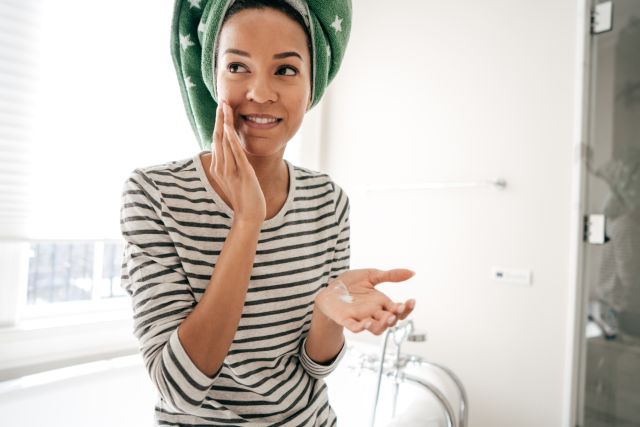 woman applying skin moisturizer in the bathroom