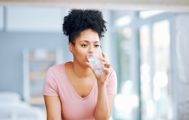 Seated young woman drinking a class of water