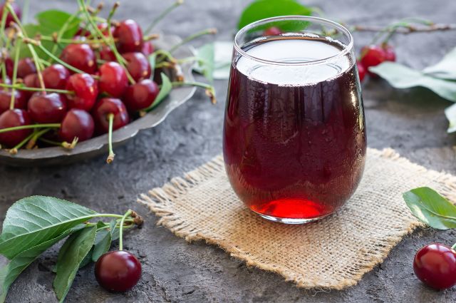 glass of tart cherry juice with cherries in the background