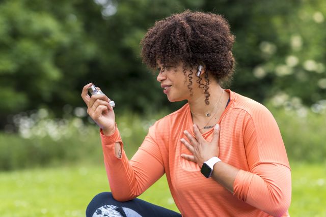 Woman with chronic asthma in a park holding an inhaler as she rests from an outdoor walk 
