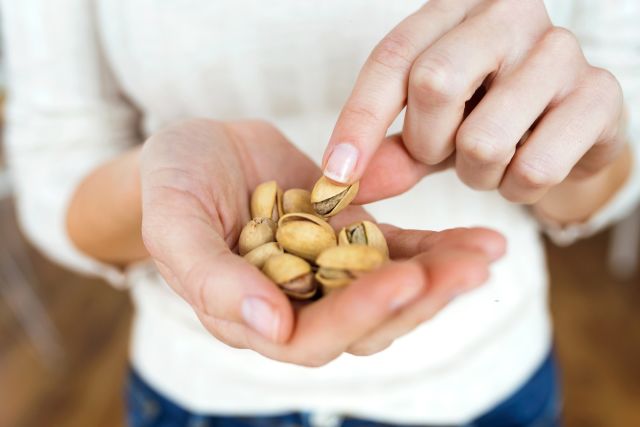 woman eating pistachios out of her hand