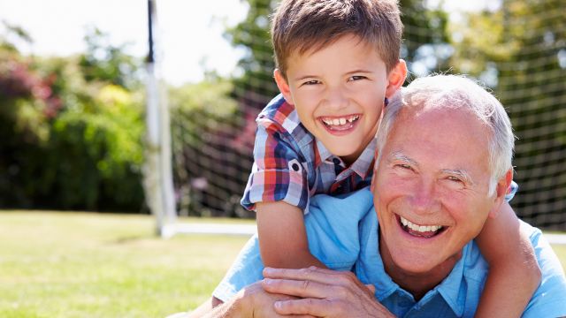 A grandfather and grandson having fun and smiling in a park.