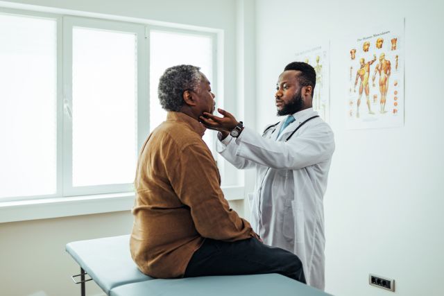 A doctor examines swollen lymph nodes in a male patient's neck. The most common symptom of mantle cell lymphoma is painless, swollen lymph nodes.