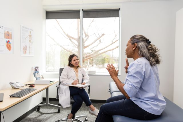 A senior woman living with HIV speaks with her primary care provider during an appointment.
