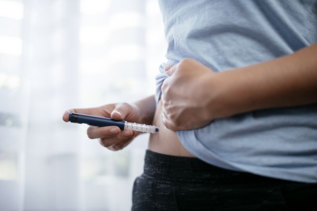 Someone injecting a medication into their lower abdomen