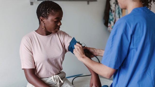 A young woman has her blood pressure taken at a healthcare appointment. Cardiovascular disease is more prevalent among people with psoriasis, and something that anyone with psoriasis should discuss with their healthcare provider.
