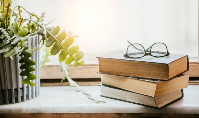 eyeglasses topping book stack next to window