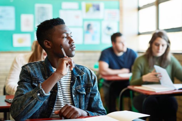 young man looking out window in classroom