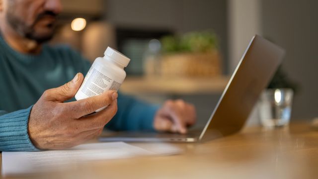 A man uses his laptop to look up a medication he has been prescribed to check for potential drug interactions.