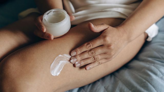 A woman applies moisturizer to her legs. Daily moisturizing is one strategy that can help ease psoriasis symptoms and prevent flares.