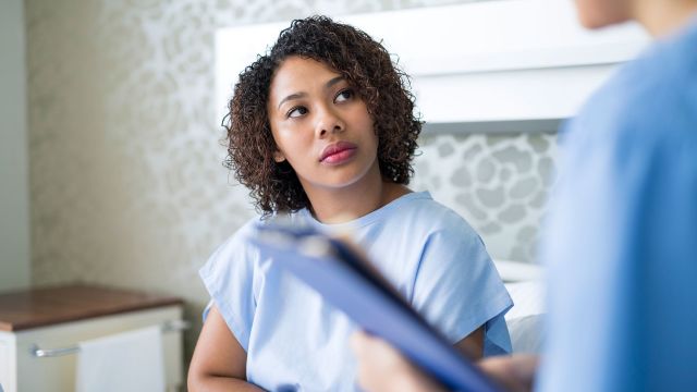 Woman in a hospital gown talking to her doctor following a colon exam