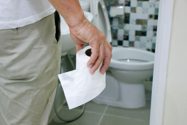 man holding toilet paper at bathroom door