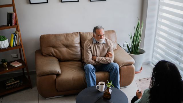 A senior man speaks with a therapist in a comfortably appointed office. Counseling is a recommended part of treatment for people with Parkinson's disease psychosis.