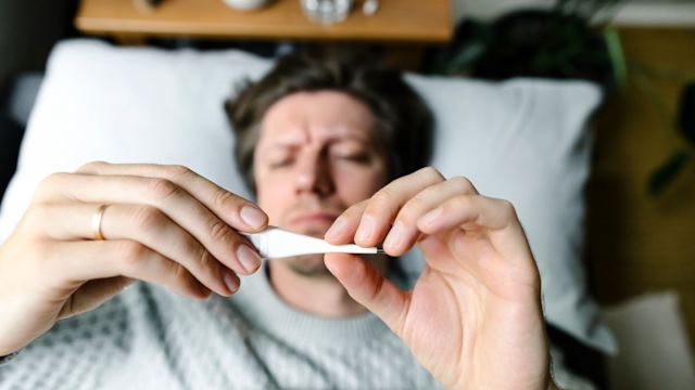 A man checks his temperature while home sick. People with diabetes should have a thermometer at home to check temperature when sick with the flu or another illness.