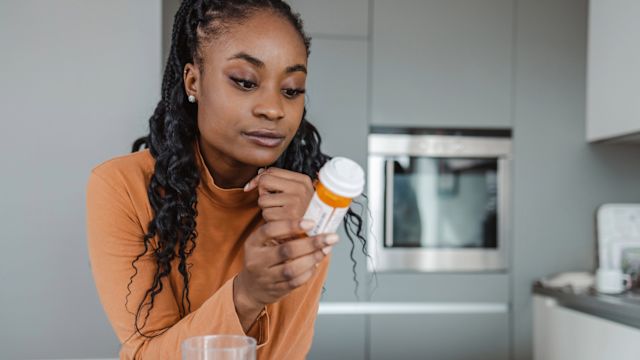 A woman reads the label on a bottle of medication. People living with depression often have coexisting mental health conditions that also require treatment.