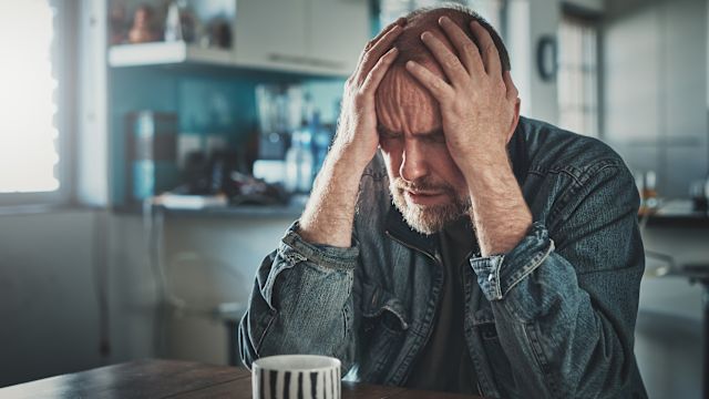 A man at a table struggles with stress, sleep debt, and depression. Shingles can have a profound impact on a person's mental wellbeing.