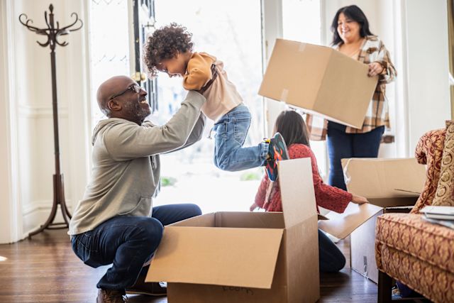 A multiracial family happily opens moving boxes in their new home