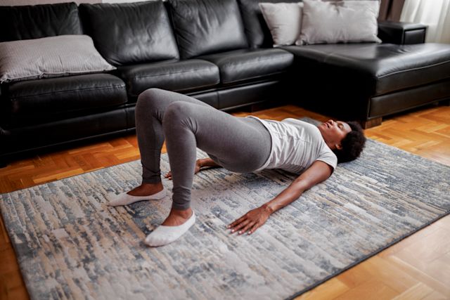 woman doing yoga bridge pose in her living room