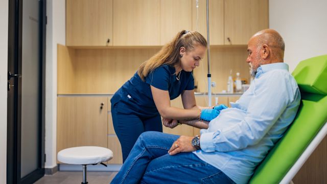 A nurse prepares an infusion for a man being treated for hATTR amyloidosis. Gene-silencing therapies to treat amyloidosis are delivered with a subcutaneous infusion.