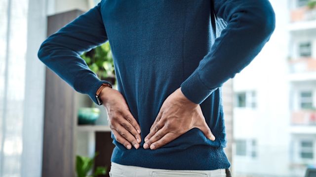 A man experiences pain in the lower back, the most common symptom of axial spondyloarthritis.