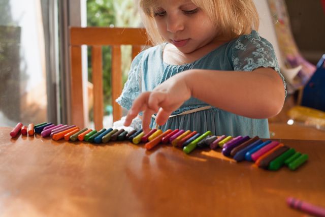 Young girl placing crayons in color order
