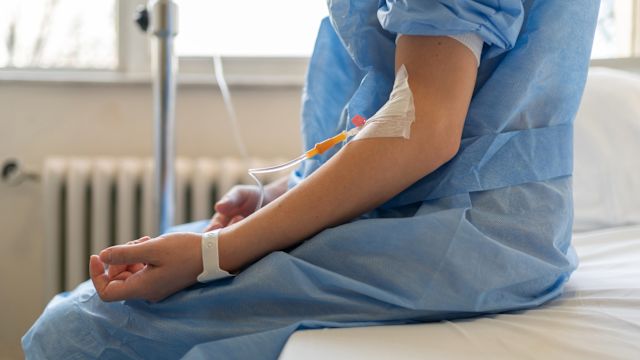 A woman receives an intravenous infusion at a hospital as part of treatment for a neuroendocrine tumor.