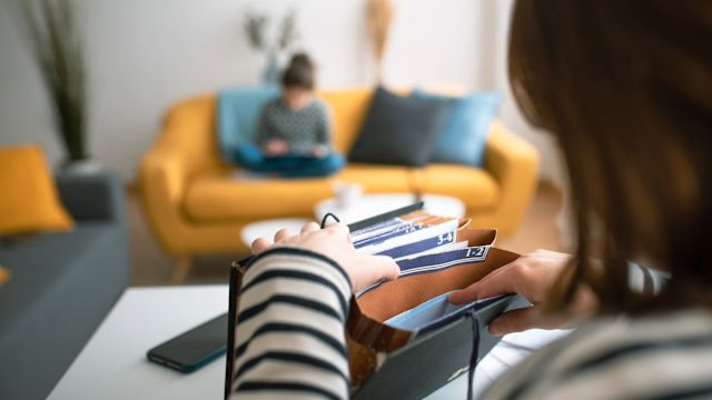 A young mother files healthcare-related paperwork into an accordion file folder while her child plays in the background. Organization is an essential strategy in coordinating care among different healthcare providers.