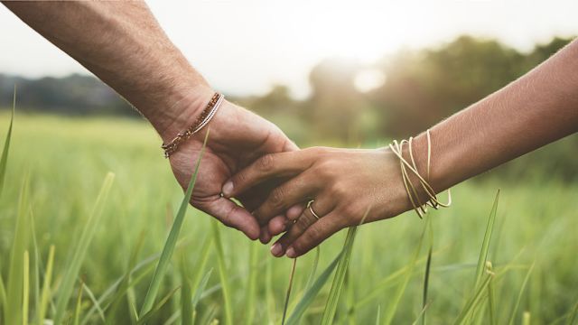 Couple holding hands in a field.