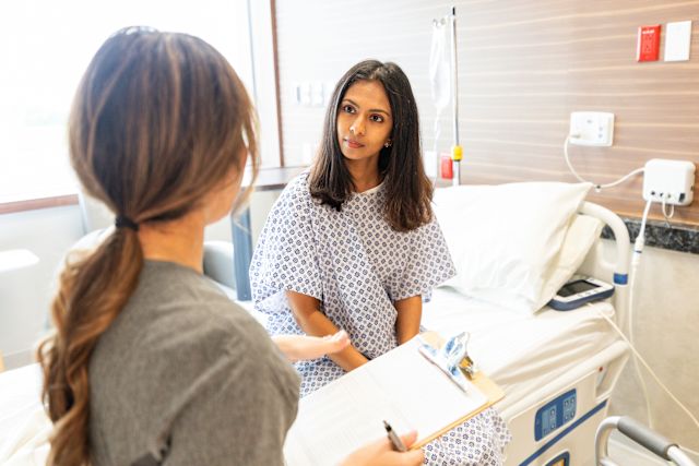 young adult female in hospital gown listening to healthcare professional during an office visit