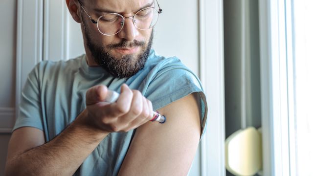 A man self-administers an injection of a medication that prevents HAE attacks in his upper arm using an injection pen.